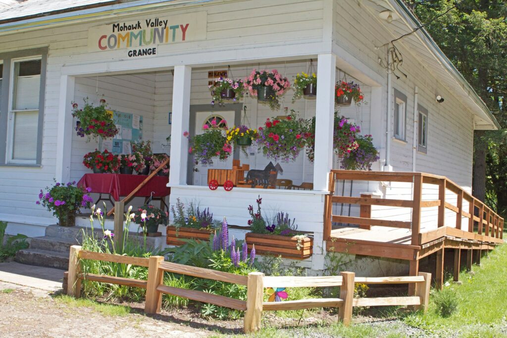 the grange porch full of hanging flower pots